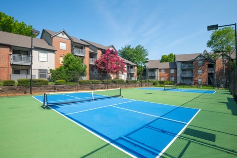 A tennis court surrounded by apartment buildings.