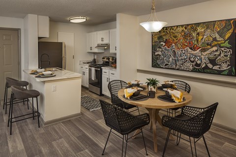 A kitchen with a table set for four with a painting hanging on the wall.