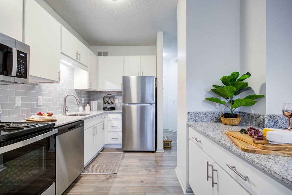 A kitchen with a stainless steel refrigerator and a plant on the counter.