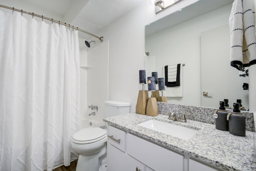 A white bathroom with a toilet, sink, and shower curtain.