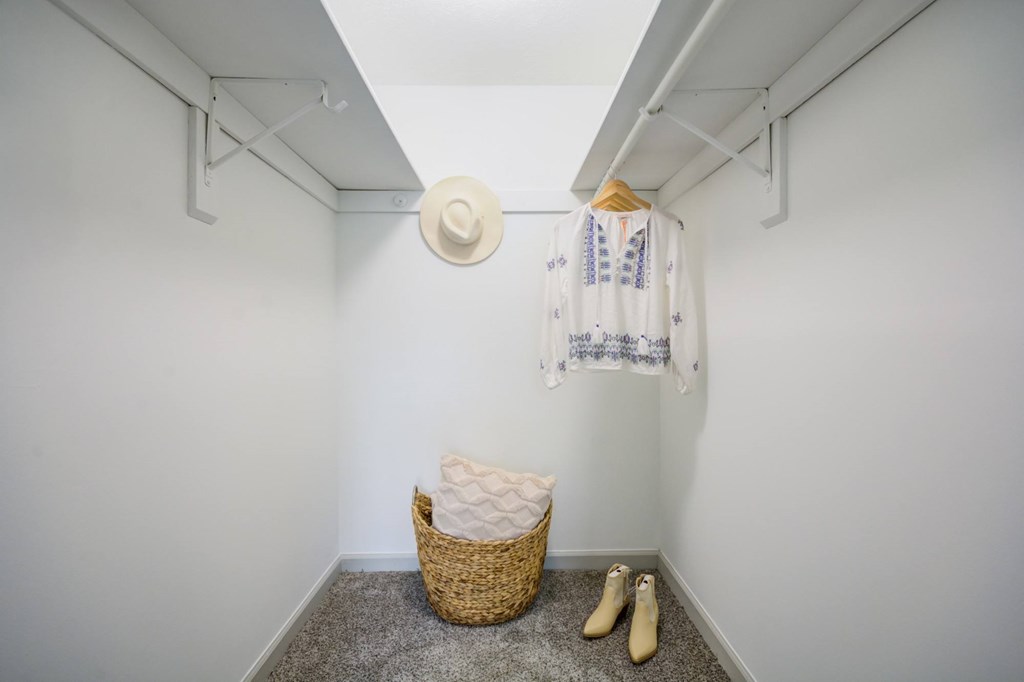 A room with a basket, a hat, a pair of slippers and a towel hanging on the wall.