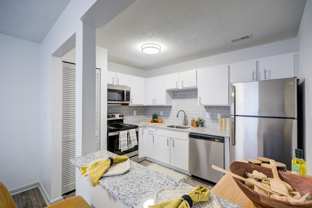 A kitchen with a refrigerator, microwave, and oven.