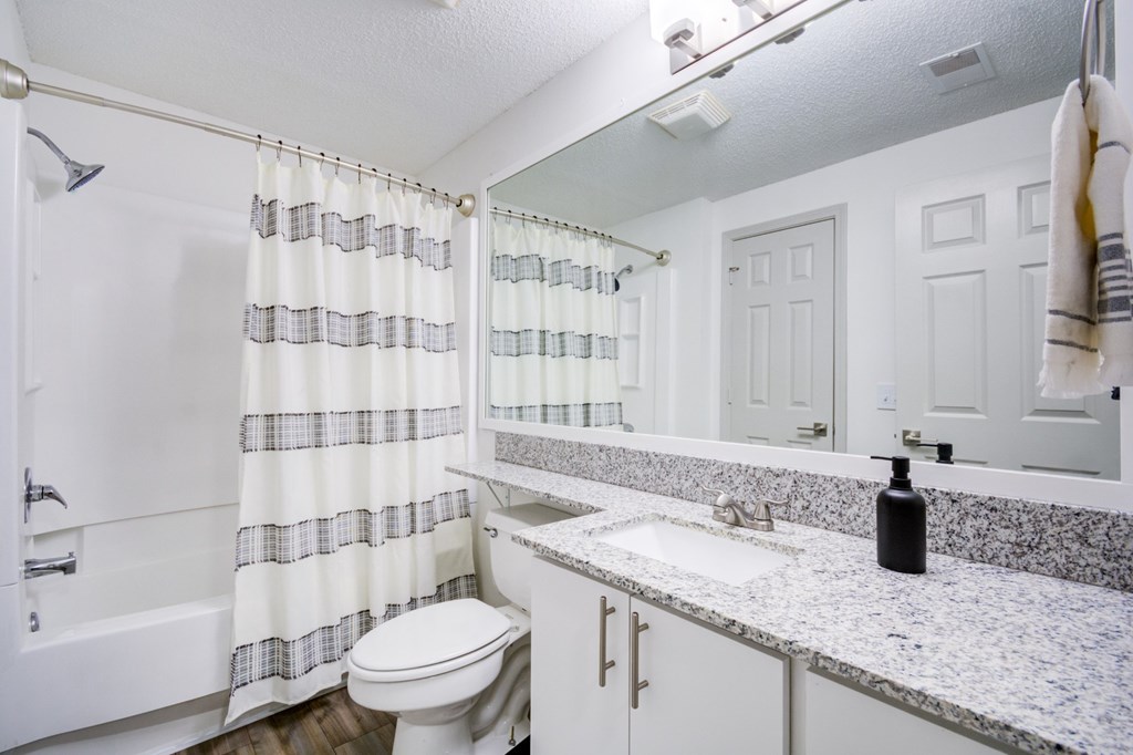A white bathroom with a toilet, sink, and shower.