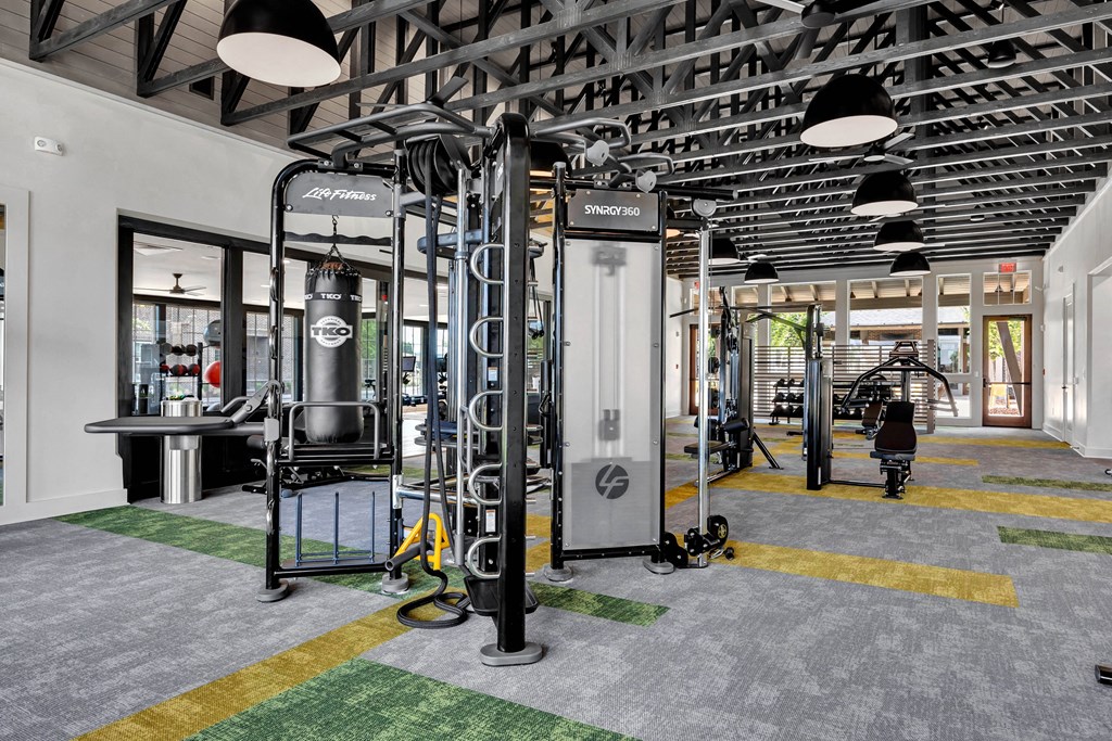 a gym with weights machines and a person walking in the background