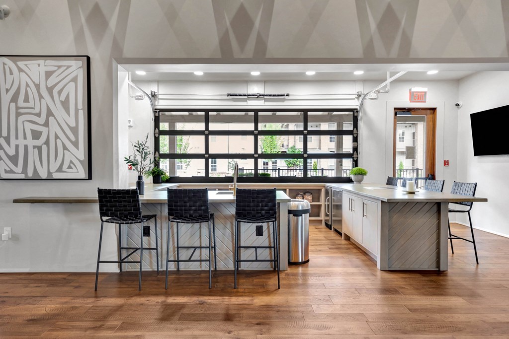 a kitchen with a bar and chairs in front of a window