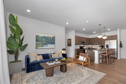 a living room with a couch and a table in front of a kitchen