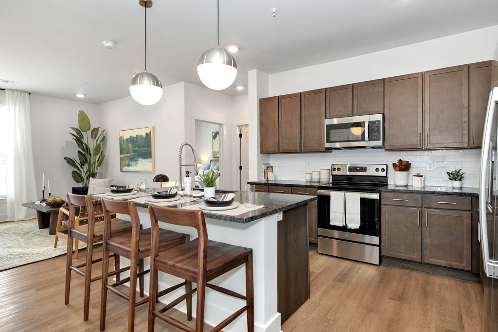 an open kitchen and dining room with wooden cabinets and a marble counter top