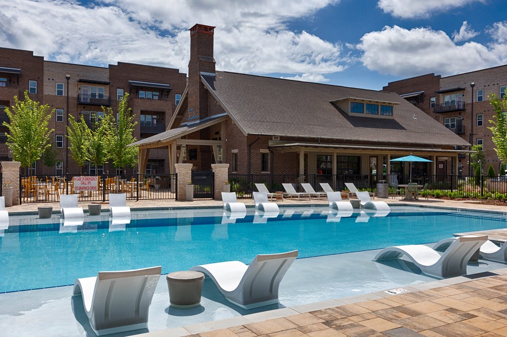 a swimming pool with lounge chairs in front of a building