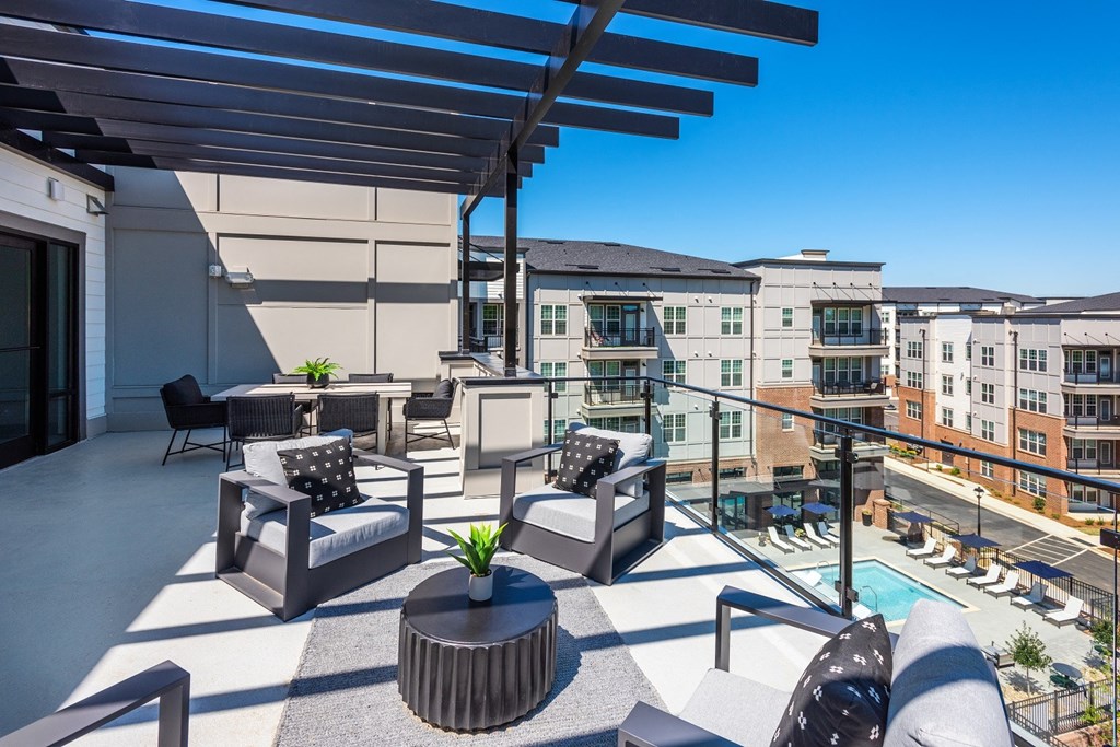 a patio with chairs and a table with a potted plant and a pool in the background at The Livano Tryon, Charlotte, NC