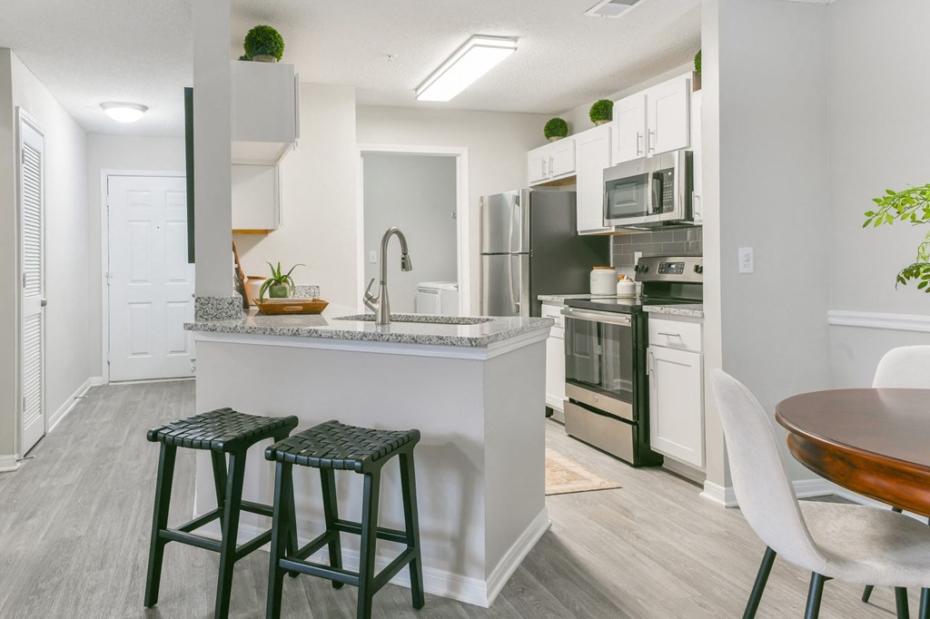an open kitchen and dining area with stools in front of a kitchen counter top at Twenty35 at Timothy Woods, Athens, GA, 30606