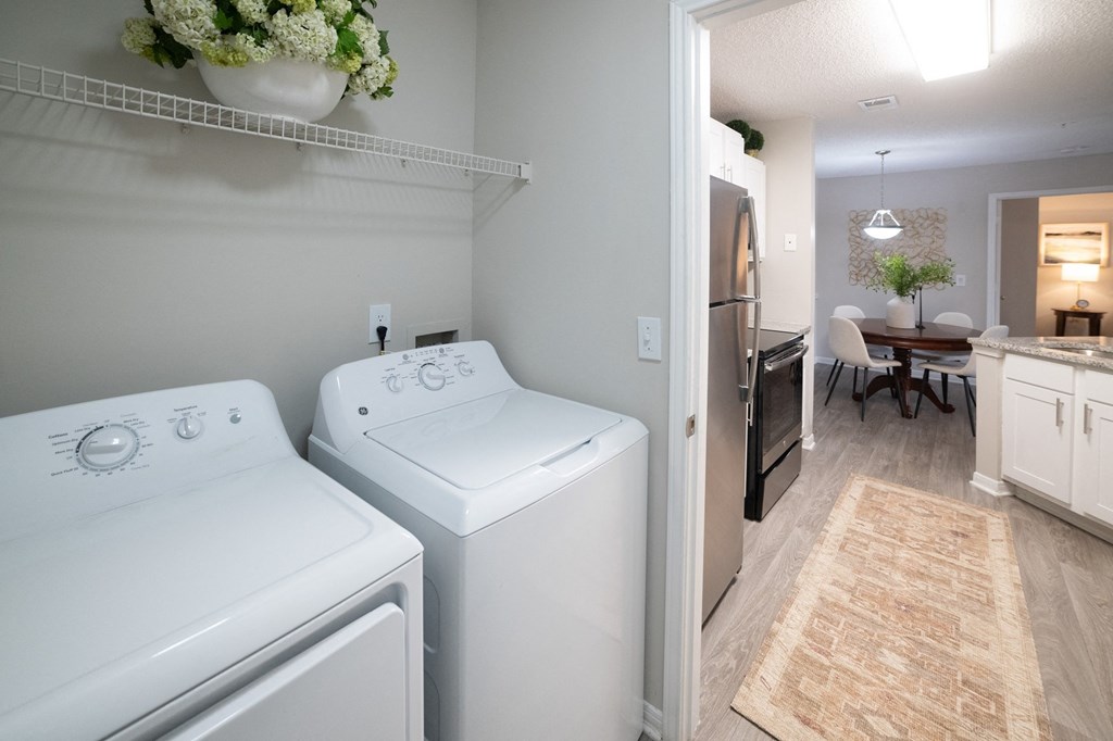 a laundry room with two washers and a dryer next to a kitchen with