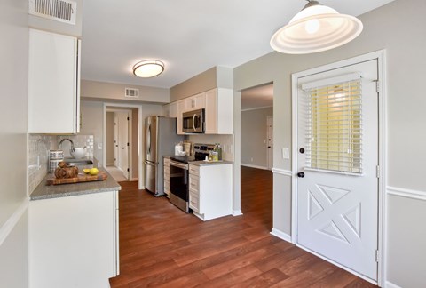 A kitchen with white cabinets and a white door.