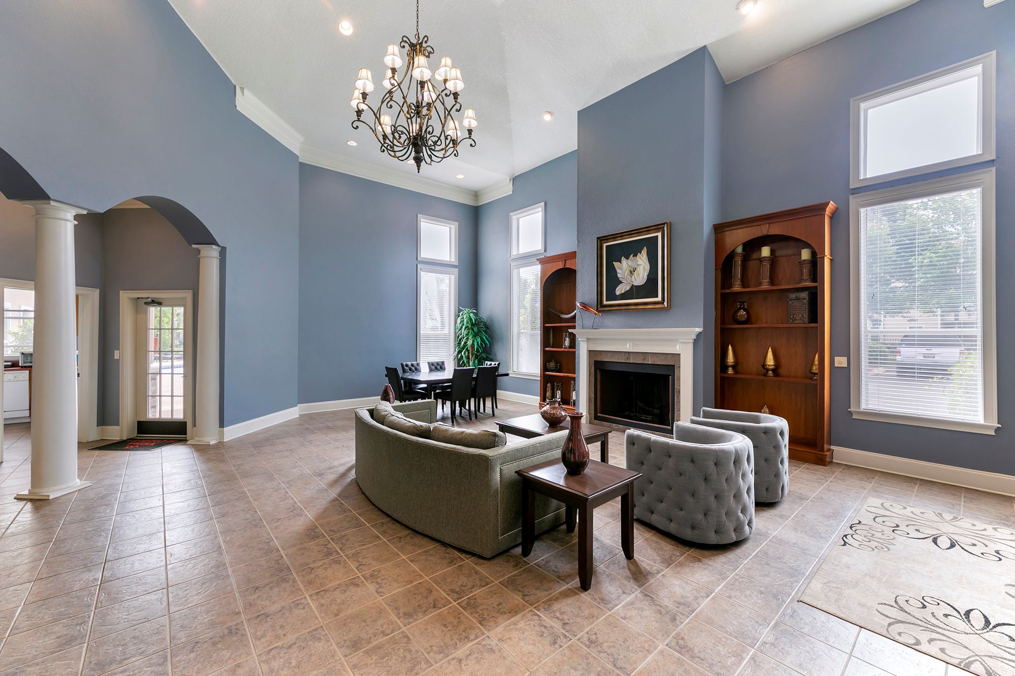 A living room with a grey sofa and a chandelier.