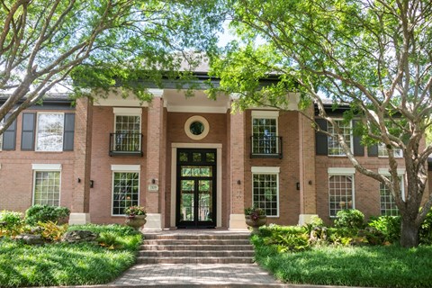 A red brick house with a black front door and steps leading up to it.