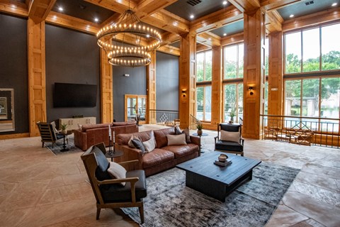 A large, well-lit living room with a variety of seating options and a television.