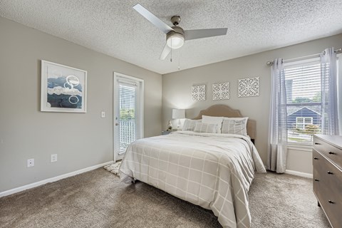 Bedroom with door to balcony and patterned bedding at Wood Terrace Apartments, Doraville, 30340