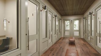 a long hallway with white walls and doors and a wood floor