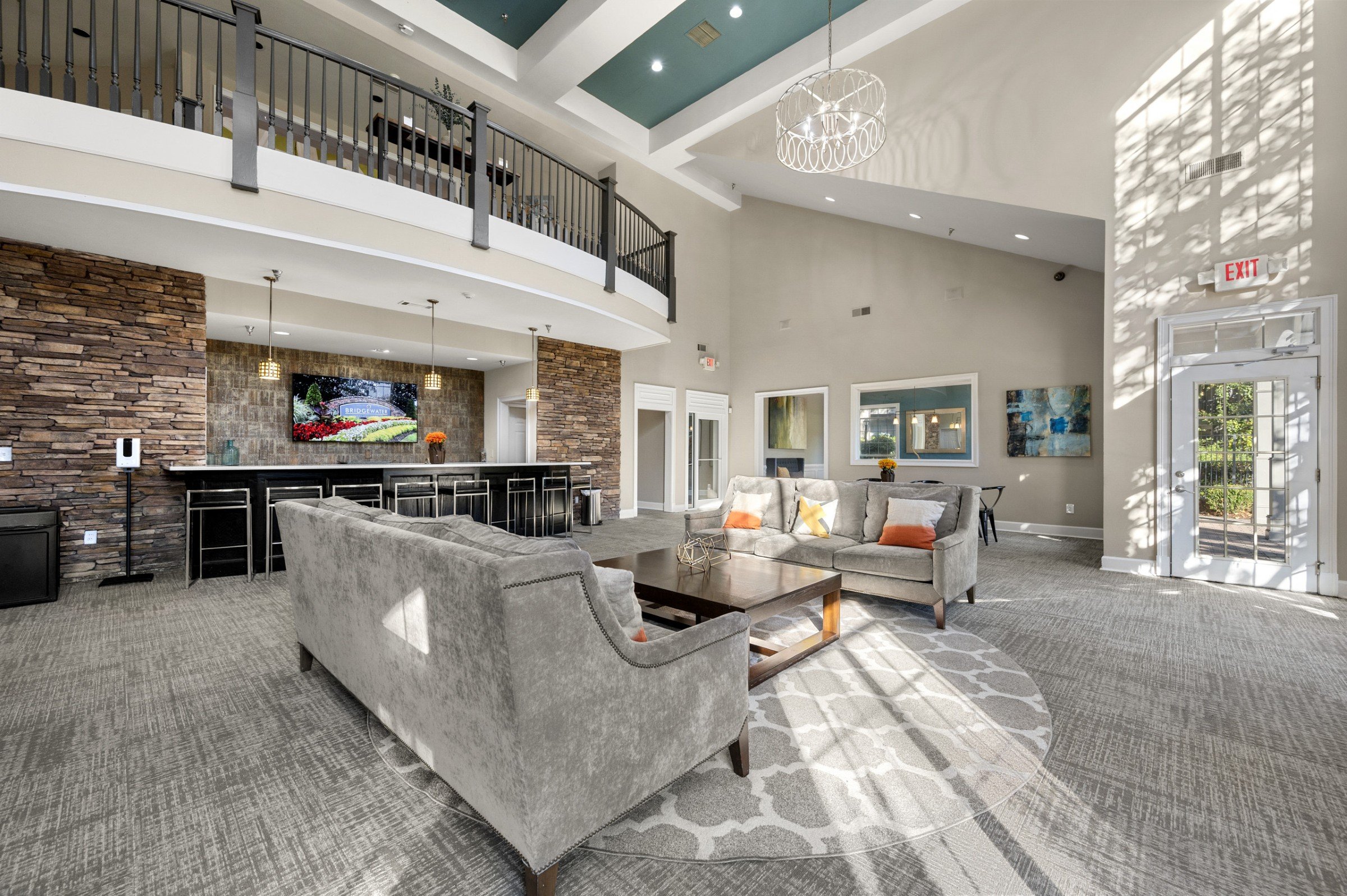 A living room with a grey couch and a stone wall.