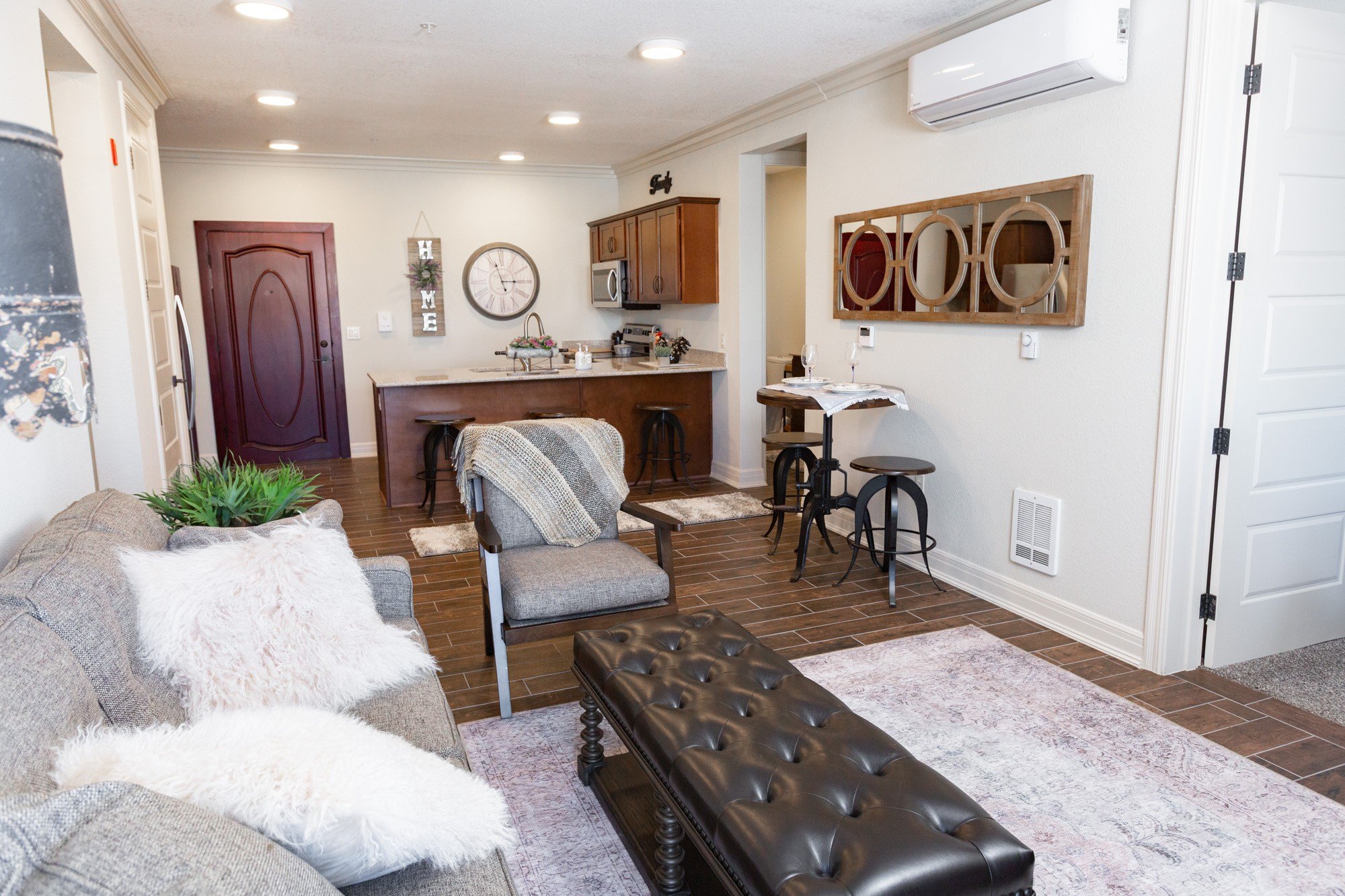A living room with a grey couch and a black leather ottoman.