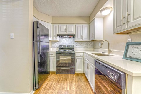 A kitchen with a refrigerator, oven, and sink.
