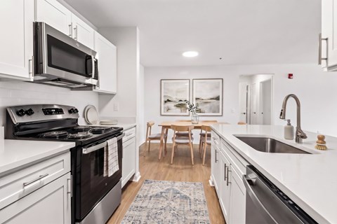 A modern kitchen with a black stove top oven and white cabinets.