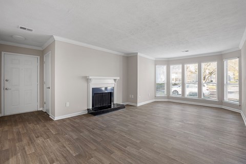A living room with a fireplace and wood flooring. at Manchester at Mansell, Roswell, GA