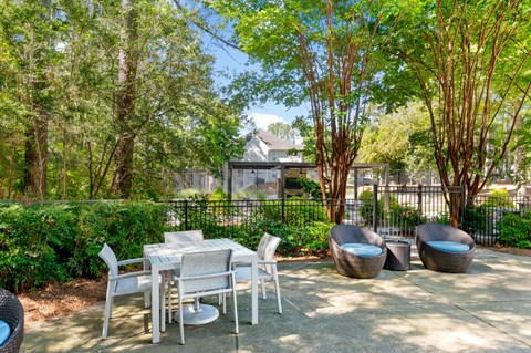 A patio with a table and chairs surrounded by trees. at Manchester at Mansell, Georgia 