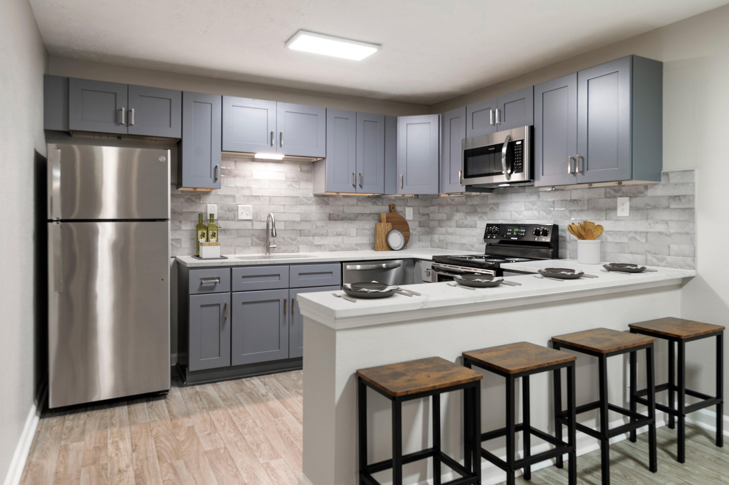 A kitchen with a stainless steel refrigerator and wooden bar stools.