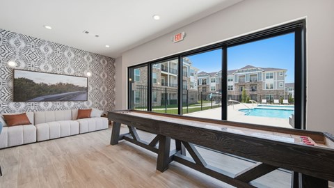 A room with a pool table and a view of a pool and apartment buildings.