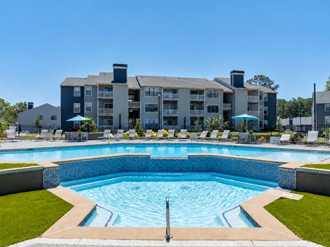 A large swimming pool in front of a multi-story apartment building.