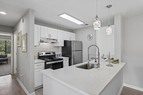 A modern kitchen with a stainless steel refrigerator, a white countertop, and a sink with a faucet.