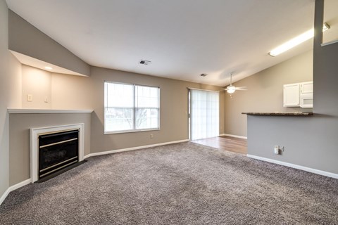 A spacious living room with a fireplace and carpeted floor.