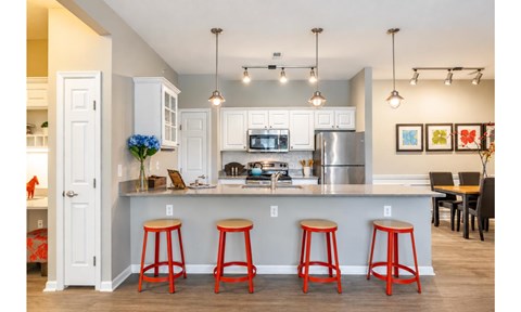 A kitchen with a bar stool in front of it.