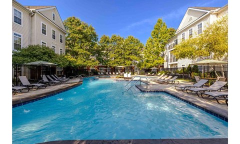 A swimming pool surrounded by lounge chairs and trees.