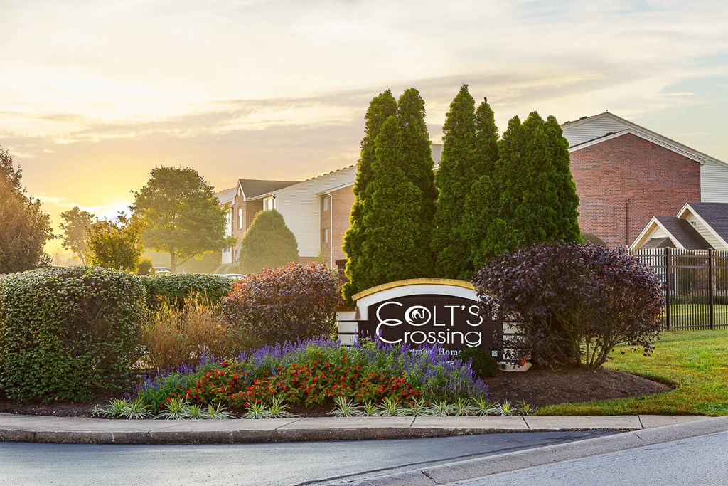 A sign for Colt's Crossing is in front of a house.