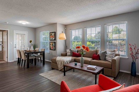 A living room with a brown couch, a red chair, and a wooden floor.