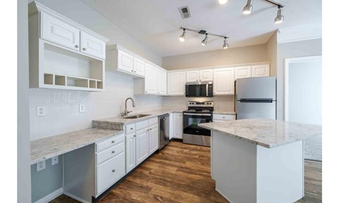 A modern kitchen with white cabinets and a marble countertop.