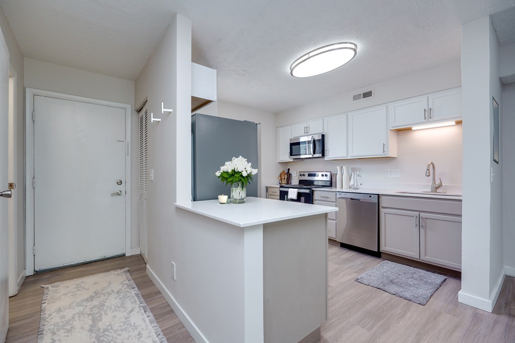 A kitchen with a white counter and a microwave on it.