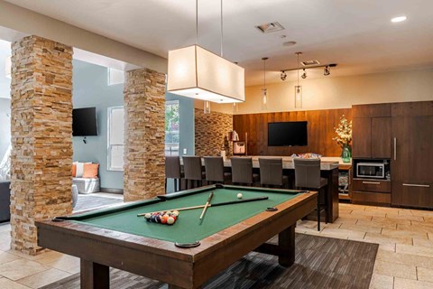 A pool table with a green cloth and a cue stick on it.