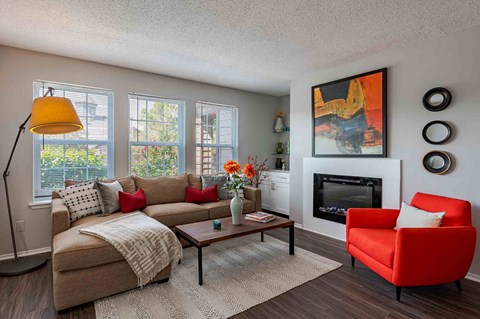 A living room with a red chair, a beige couch, and a fireplace.