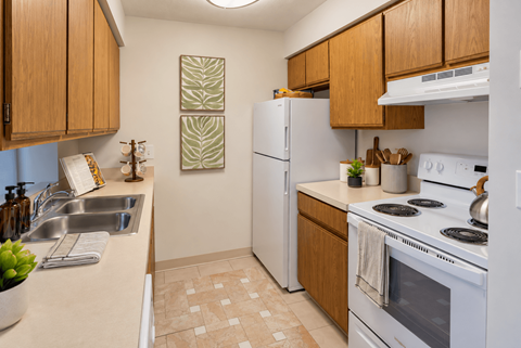 A kitchen with a white refrigerator, white stove, and wooden cabinets.