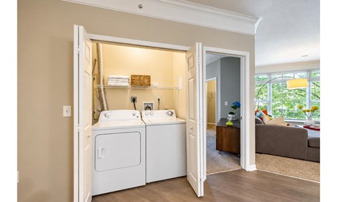 A bathroom with a double sink and a washer and dryer built into the cabinetry.