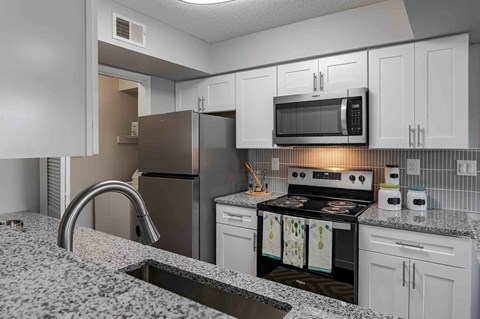 A kitchen with a granite countertop and stainless steel appliances.