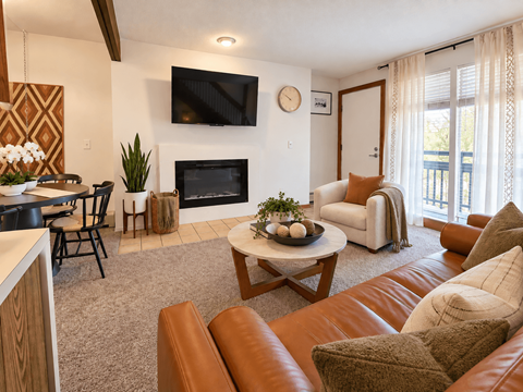 A living room with a fireplace and a flat screen TV mounted on the wall.
