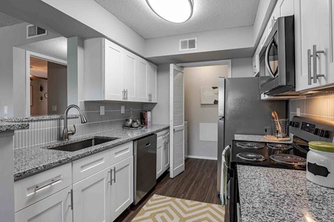 A kitchen with white cabinets and a black refrigerator.