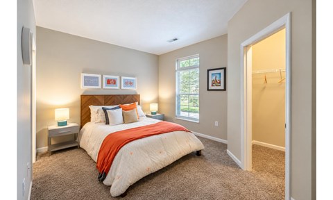 A bedroom with a bed, nightstands, and a window.