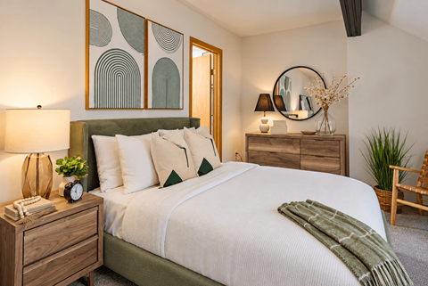 A bedroom with a bed, nightstand, and a plant.