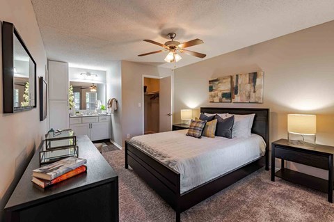 A bedroom with a bed, nightstand, and a ceiling fan.