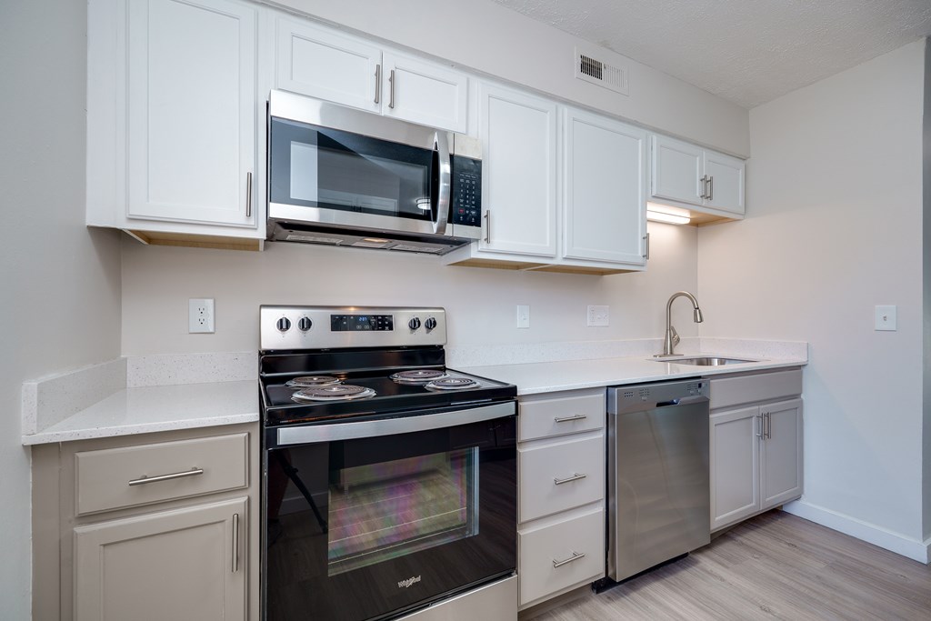 A kitchen with white cabinets and a stove top oven.