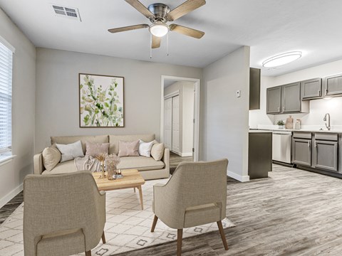 A living room with a beige couch, two chairs, and a dining table.